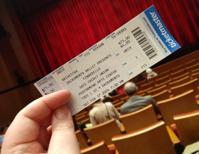 a ticket for Cinderella held up in front of the closed stage curtain