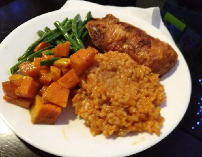 Roasted chicken breast, thai curry risotto, butternut squash and green beans on a plte