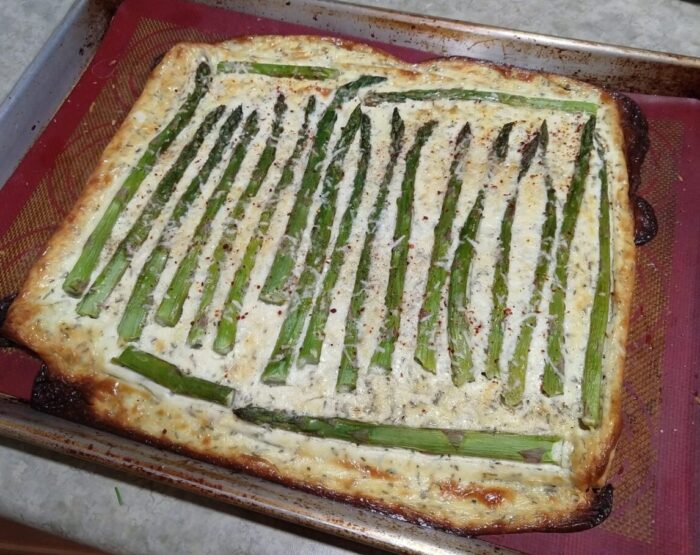 Asparagus lined up on top of a tart made of puff pastry and a goat cheese mixture