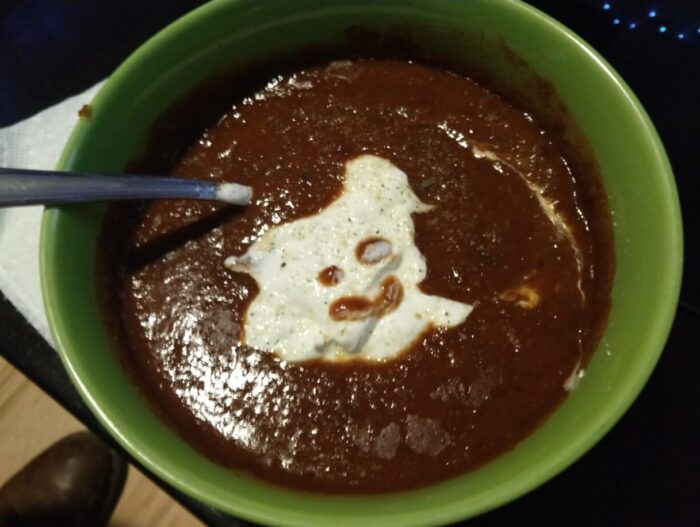 a bowl of soup topped with sour cream. A little happy face has been drawn in the sour cream
