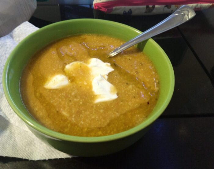 a bowl of corn soup topped with sour cream and chili oil