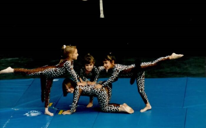 Me, six years old, on hands and knees while three other girls lean on me for balance in an arabesque
