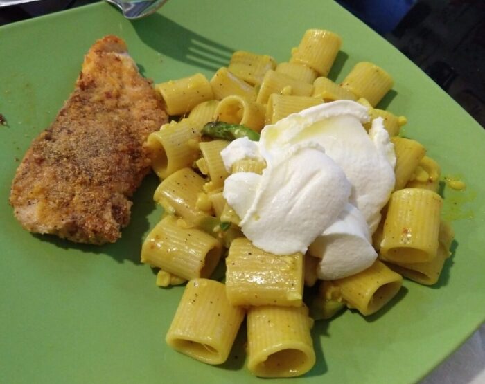 a plate of corn and asparagus pasta with a big dollop of ricotta on top, and a piece of pan-fried chicken