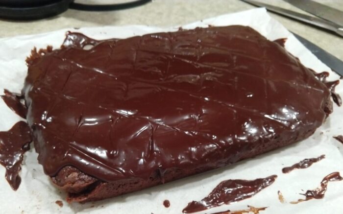 A big, rectangular chocolate cake topped with glossy chocolate ganache