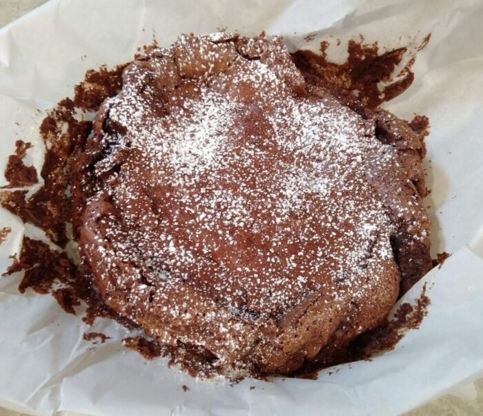 A round flourless chocolate cake dusted with powdered sugar