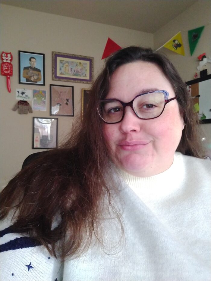 Me with my hair down and wearing a bulky white sweater. I'm in my office and there is various artwork on the wall behind me.