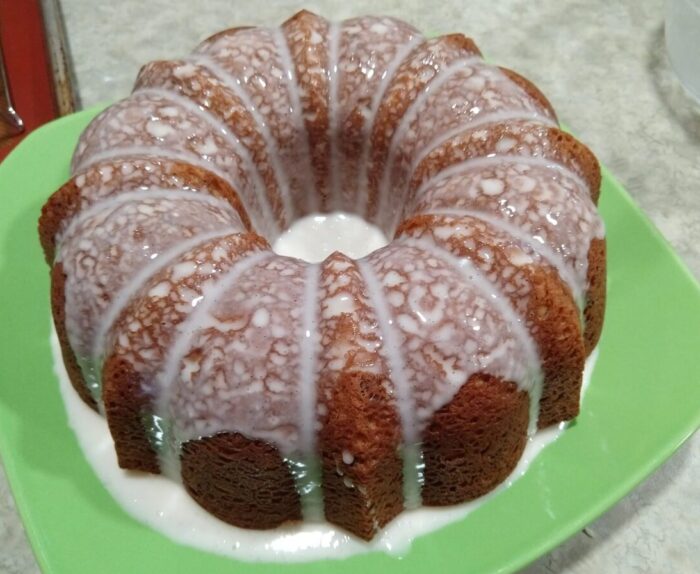 Bundt cake drizzled with vanilla glaze that is too runny and is pooling on the plate