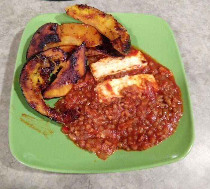 a plat of farro and lentils in tomato sauce topped with feta; roasted slices of acorn squash