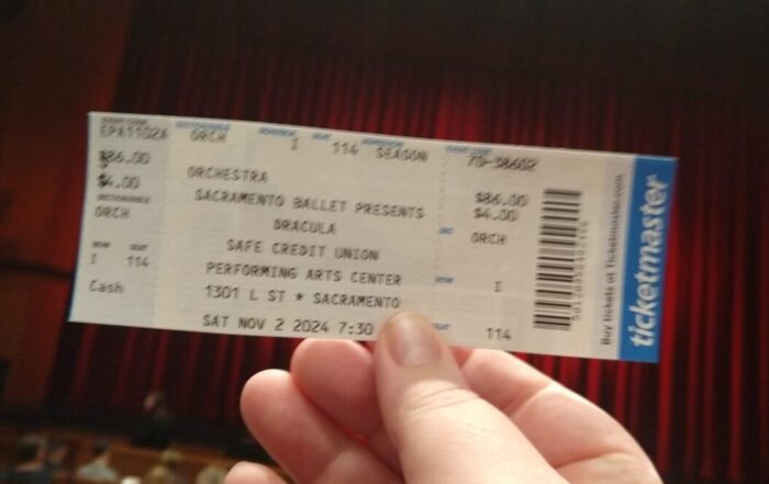 ticket for Sacramento Ballet presents Dracula held up in front of a closed red stage curtain