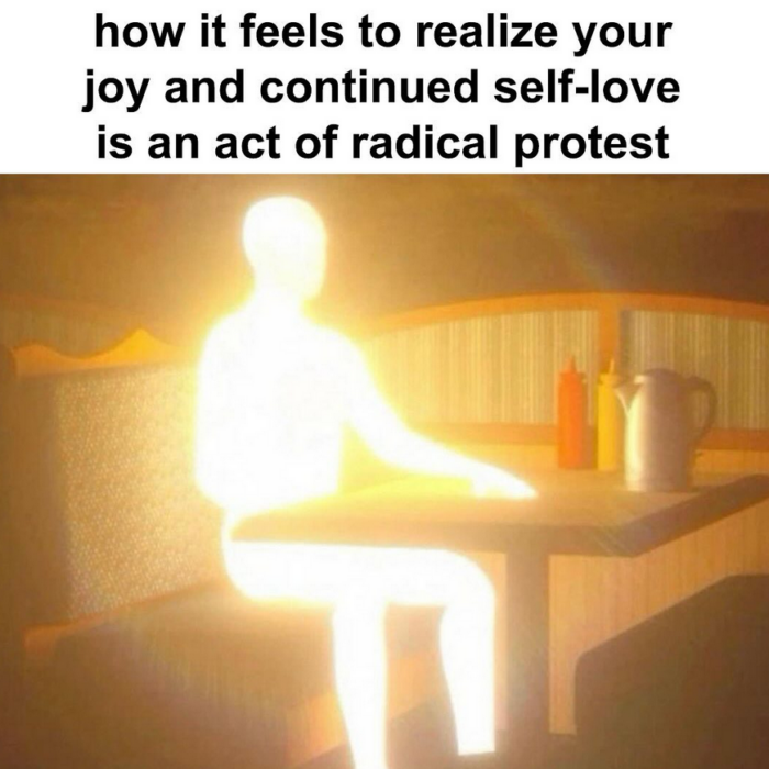 A meme with a man sitting in a diner booth, glowing brightly so we can't see any of his features. Text reads "how it feels to realize your joy and continued self-love is an act of radical protest."