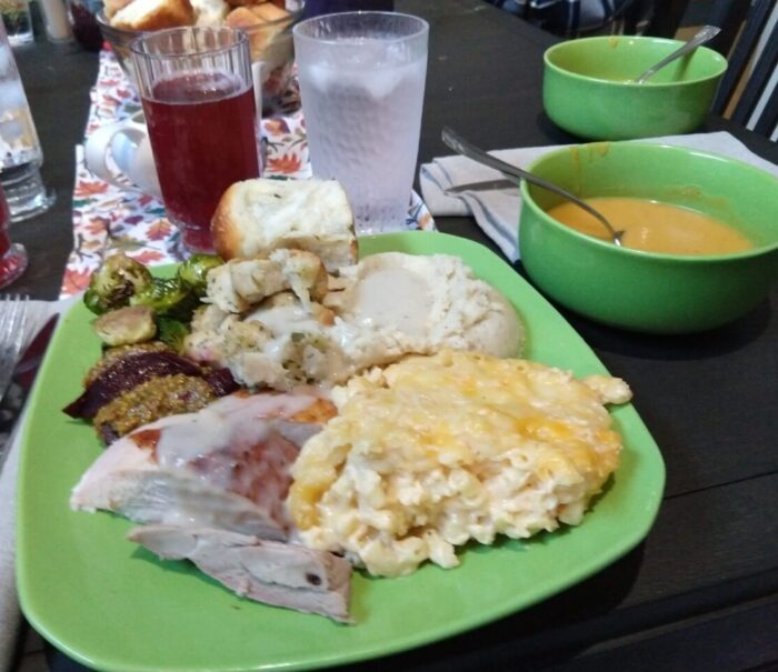 a plate heaped with thanksgiving foods, a bowl of soup, and a glass of punch