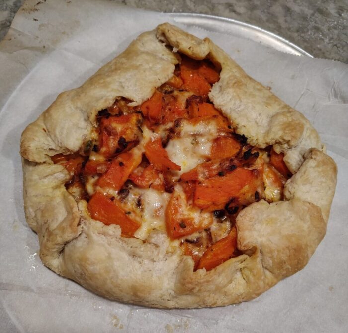 a freshly baked caramelized onion and butternut squash galette resting on parchment paper