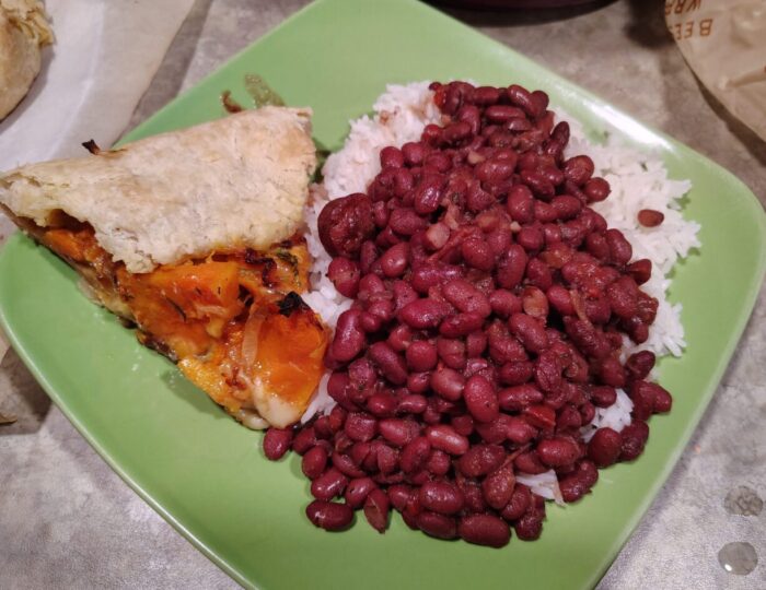 a plate with a pile of red beans and rice and a slice of butternut squash galette