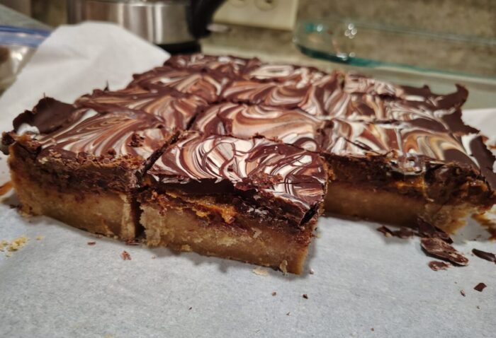 cross section of million peso shortbread, a cookie with a shortbread base, caramel layer, and marbled white and dark chocolate on top.