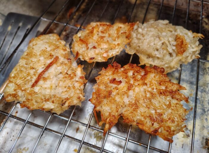 Freshly fried latkes on a wire rack above a sheet pan. The picture is kinda ugly to be honest but the latkes were good