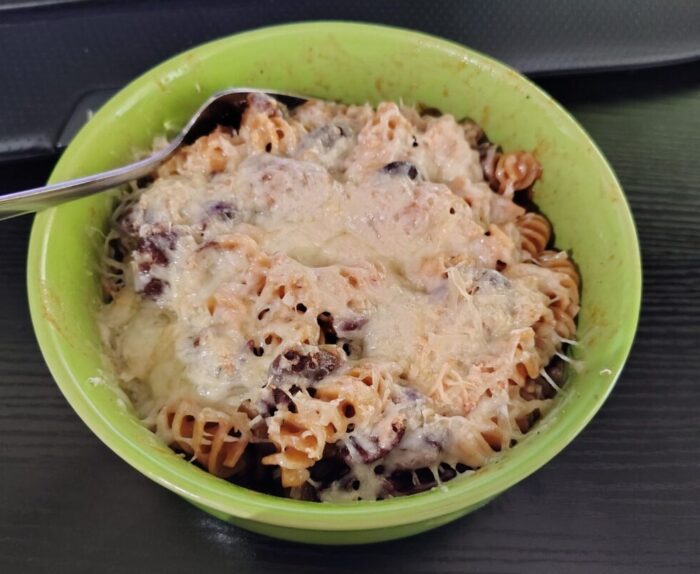 A bowl of serbian baked beans mixed with pasta then topped with melty cheese