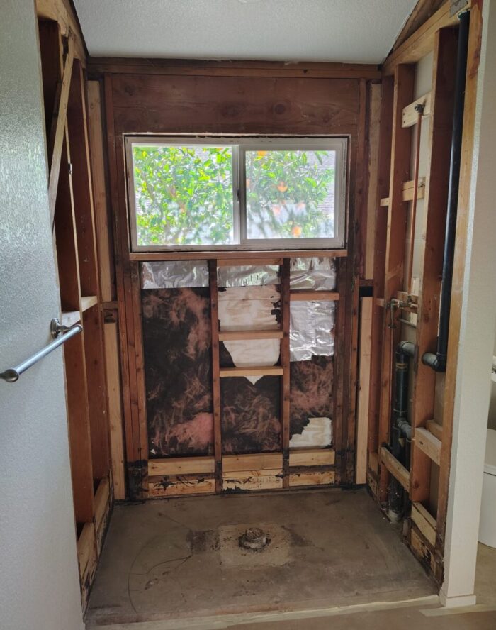 The space where my shower has been removed, exposing the inner walls, pipes, and insulation