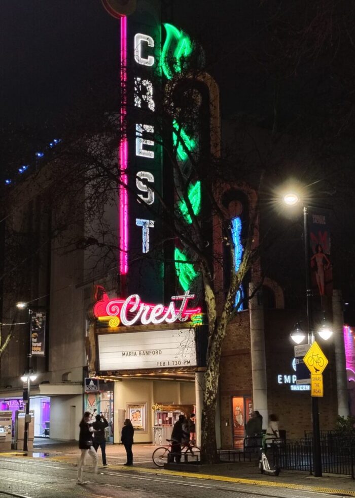 Big neon sign announcing the Crest theater with the marquee listing "Maria Bamford"