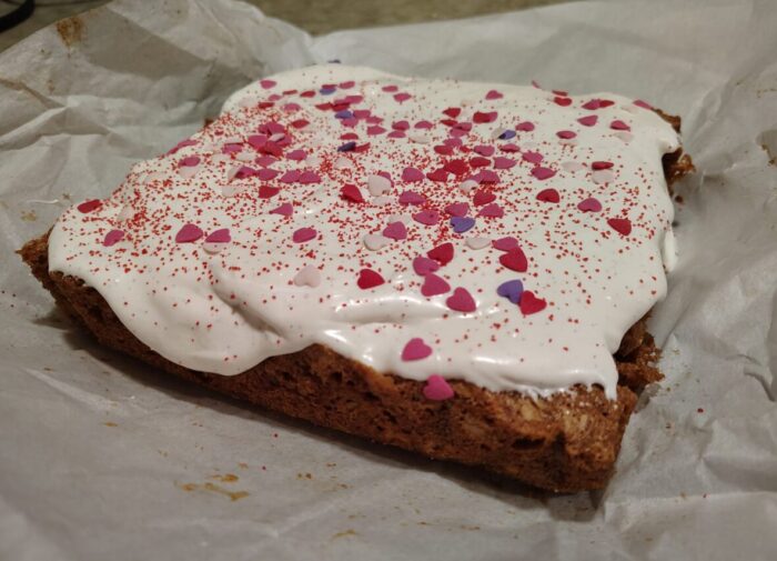 a big, square cookie topped with marshmallow creme frosting and heart sprinkles