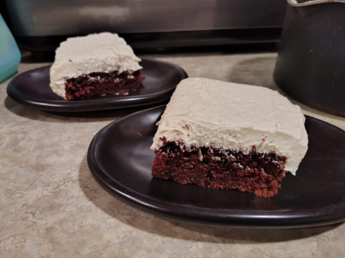 two small plates with rectangular cake slices. The frosting is almost as thick as the cake