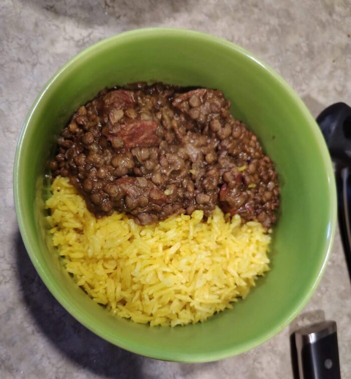 A bowl of bright-yellow rice paired with a lentil and linguica stew