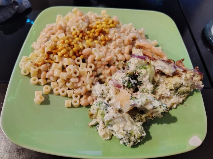 a plate with a pile of tiny noodles with pesto beans on top. The beans are topped with toasted pine nuts. A slice of what is theoretically a tart but got ugly on the way to my plate, so it's just a blob of broccoli, onion and cream sauce