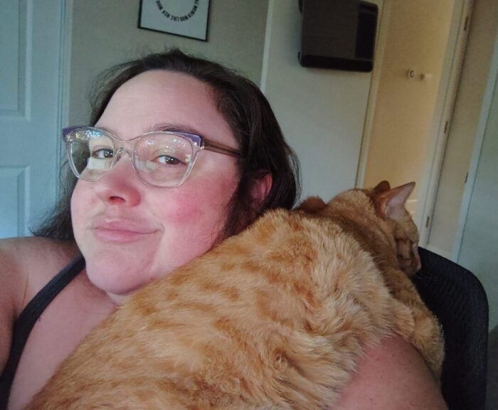 Fritz the cat draped over my shoulder and just chilling out. I am smiling at the camera