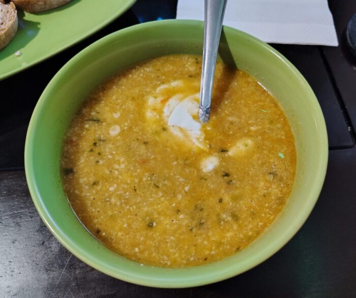 A bowl of corn soup topped with a dollop of sour cream