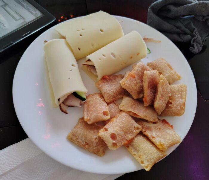 a plate of turkey rolled up with swiss cheese and a pile of pizza rolls