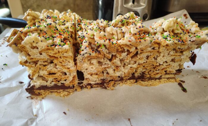 cross-section of smores rice krispie treats, with graham cracker base and golden grahams mixed with the rice krispies