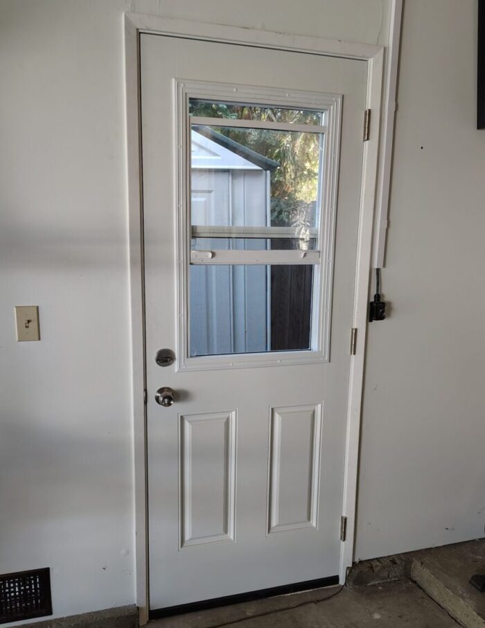 A door off the side of my garage with a window built in. The window is open and there's a screen to keep out the bugs