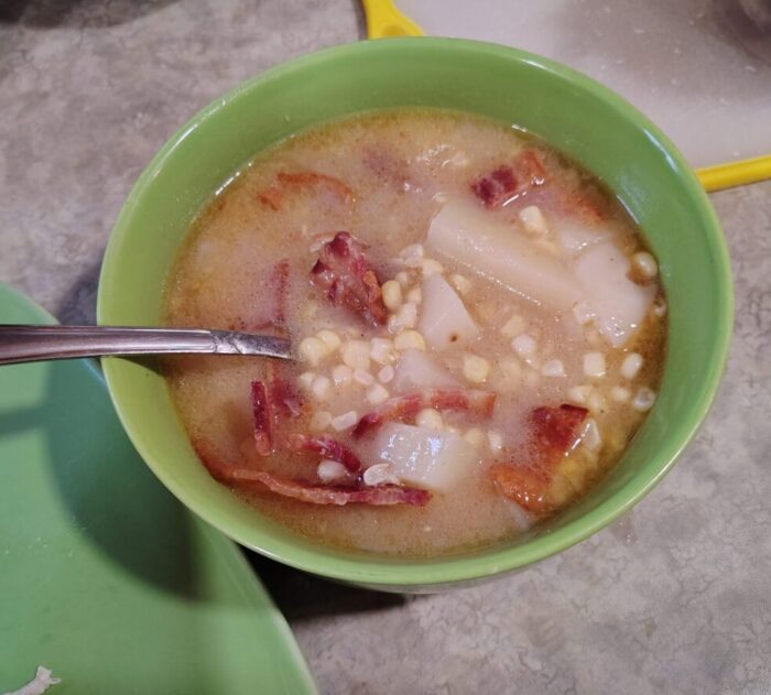 a bowl of corn and potato soup topped with bacon