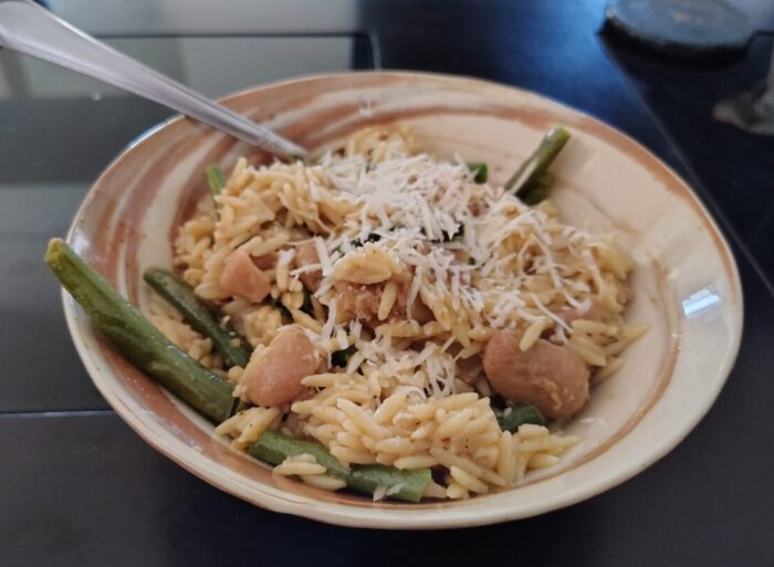 a bowl of orzo, green beans, and royal corona beans topped with parmesan cheese