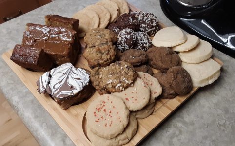 a wooden board covered in a variety of holiday cookies