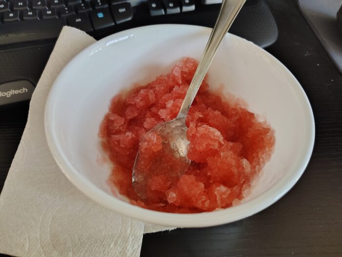 a bowl of shaved ice covered in red cherry syrup