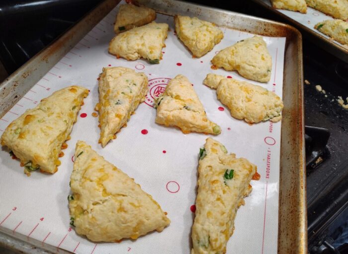 a baking pan with freshly baked scones. There is melty cheese visible and little bits of green onions