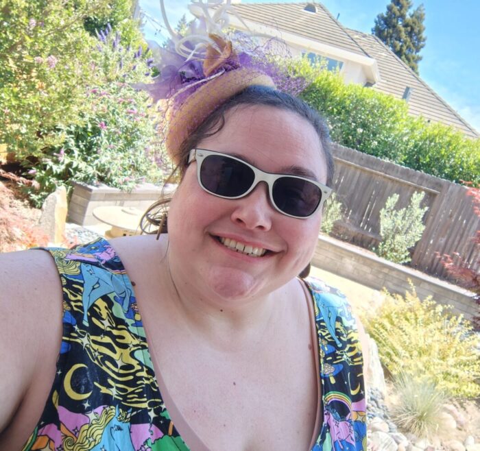 me in sunglasses and a fancy hat, smiling at the camera. I'm wearing a dress with a magical unicorn print