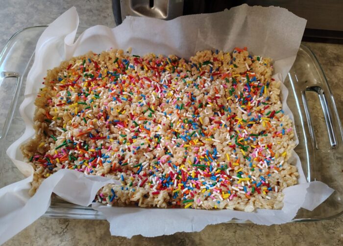 a pan of rice krispies treats generously topped with rainbow sprinkles