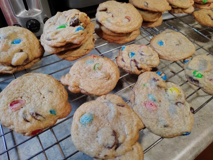 a batch of chocolate chip and M&M cookies cooling on a wire rack