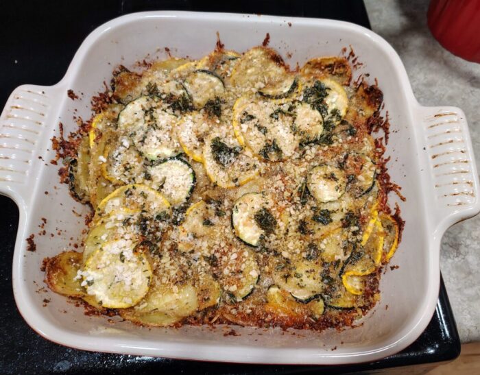 A casserole dish of zucchini gratin with lots of melty cheese bits