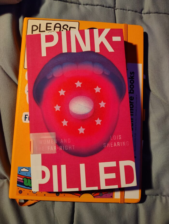 paperback book: Pink-Pilled featuring a pink cover and a tongue with a pill on it
