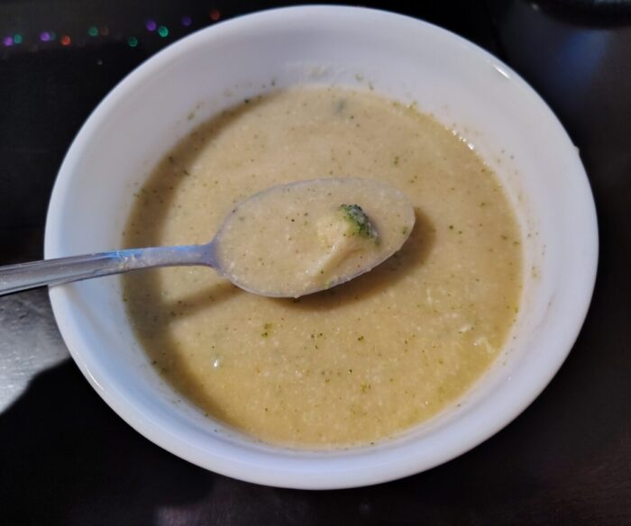 a bowl of broccoli-cheddar soup. It's a golden color with little broccoli flecks throughout