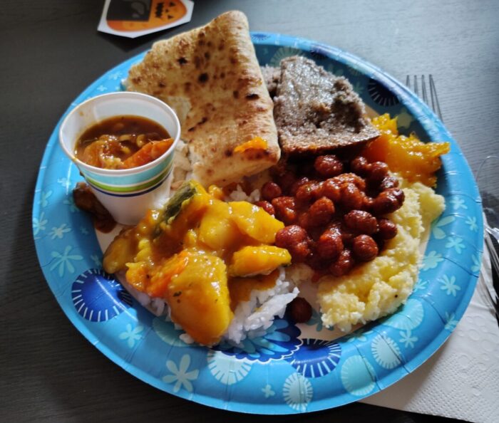 a paper plate with a variety of foods made with beans, corn, and squash