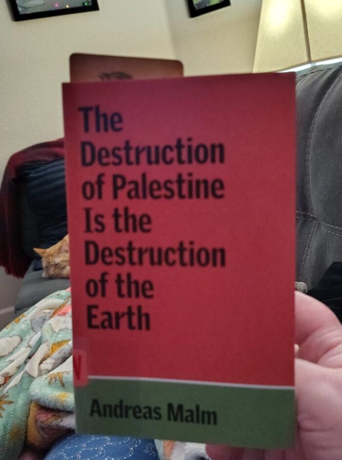 paperback book The Destruction of Palestine Is the Destruction of the Earth. Fritz the cat is snoozing in the background