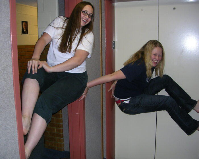 Me, 18 years old, perching in a doorway with my back pressed to one side and my feet to the other. Another girl is trying to copy my technique with limited success.