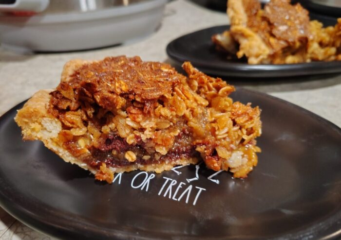 a slice of black-bottom oatmeal pie on a small plate. A layer of chocolate ganache is visible below the oat layer