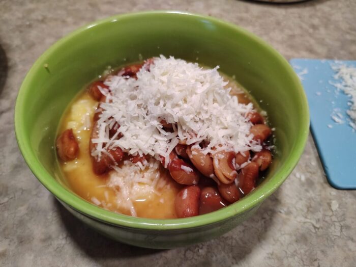 a bowl of polenta topped with brothy beans and a big pile of parmesan cheese
