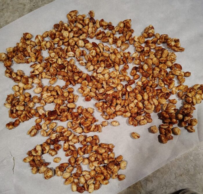 a sheet of parchment paper with a punch of caramelized peanuts cooling on top