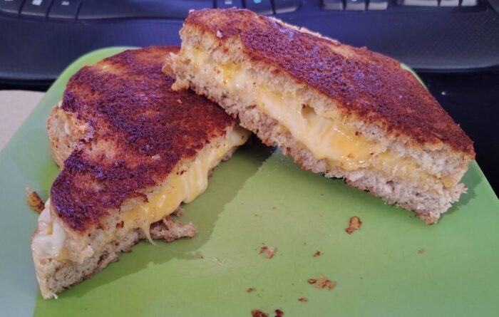 a grilled cheese, cut in half on the diagonal, with melty cheese oozing out