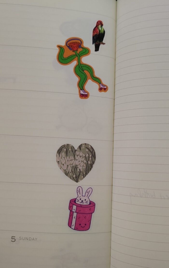 four stickers in my planner, a parrot, an anthropomorphized flower on roller skates, a heart, anda mischevious bunny